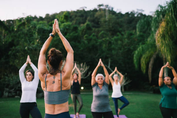 istock Group of women practicing Yoga outdoors with a instructor 2166104713