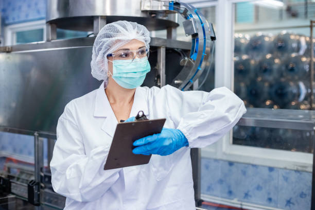 istock Female worker take note checking quality drinking water before process of filling water into plastic bottles to bring out to consumers. Water bottles on production line of factory. 2166111565
