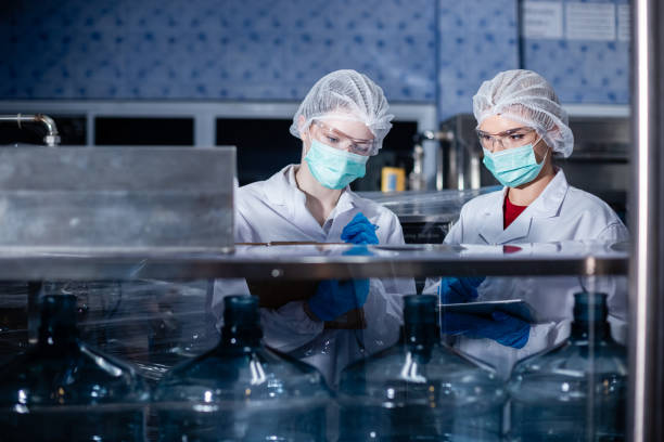 istock Female worker using tablet checking quality drinking water before process of filling water into plastic bottles to bring out to consumers. Water bottles on production line of factory. 2166111572