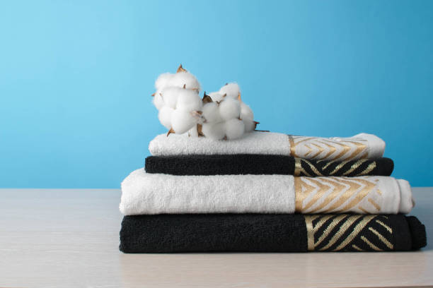 Stack of Black and White Towels with Cotton, Against Blue Background