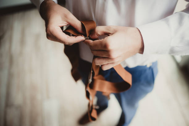 A groomsmen fastening tie on the grooms neck