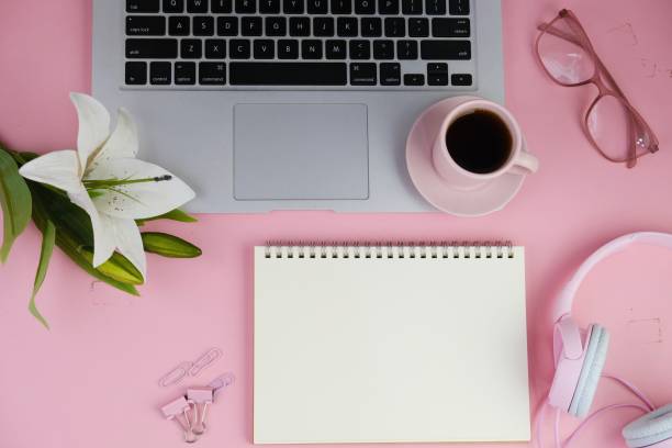 istock Flatlay of coffee with office tools, pink headphone, laptop, spectacles, notebook, pen and a bouquet of white daisy on pink background as copy space concept 2166121242