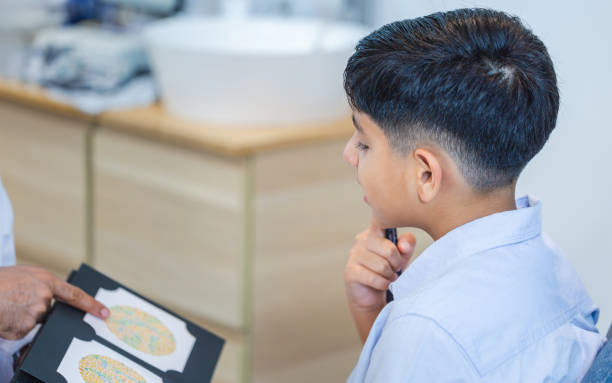 istock Boy doing eye test checking examination with optometrist in optics store, Optometrist doing color blindness disease perception test in optical shop 2166122748