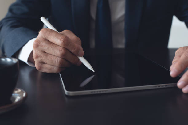 istock Close up, businessman using stylus pen signing e-document on digital tablet at office, E-signing, electronic signature concept. Business man online working on computer devices on office desk 2166125197