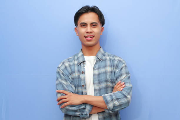 istock Handsome young Asian man showing smiling friendly expression while crossed arms with confident gesture on isolated blue background 2166126051