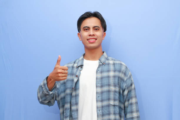 istock Handsome young Asian man posing OK sign or approve sign with hand while smiling friendly on isolated blue background 2166126080