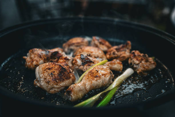 istock Grilled Chicken Drumsticks with Green Onions on a Hot Pan 2166130419