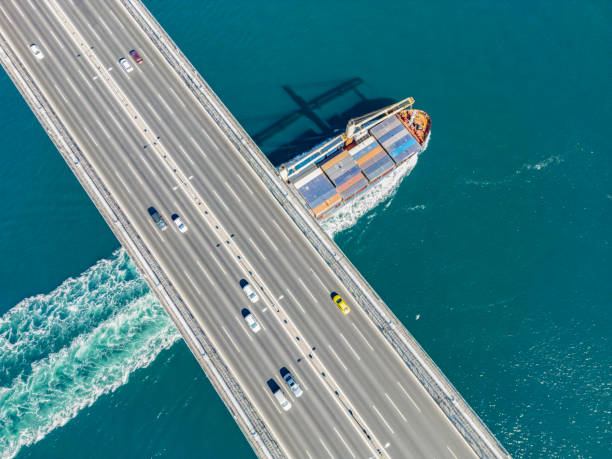istock Aerial view of a cargo ship passing under bridge. Cargo Ship Beneath Bridge. 2166132301