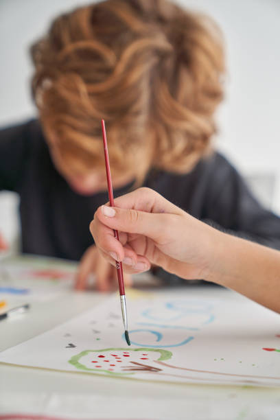 istock Unrecognizable kid painting near boy at table 2166135723