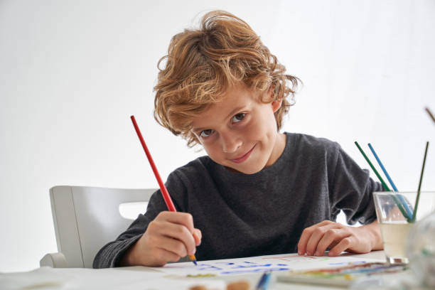 istock Cheerful boy painting at table 2166135797