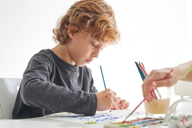 istock Focused boy painting with paintbrush 2166135838