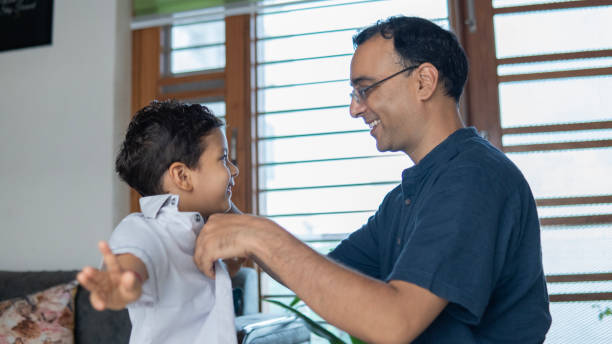 istock Man helping son in getting dressed for school at home 2166140529