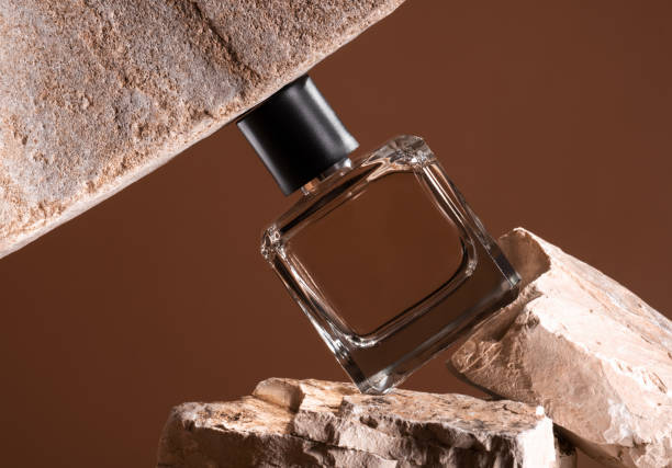 istock Perfume  transparent bottle is enclosed between stones on brown background. 2166140558