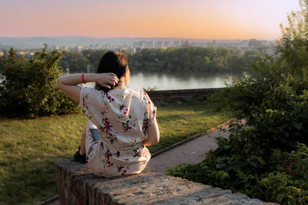 Woman solo traveler using digital tablet for orientation with online map or reading e book by the river. Tourist sightseeing.