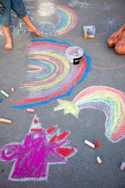 istock Children draw a rainbow on the asphalt with colored chalk. Sidewalk. 2166143448