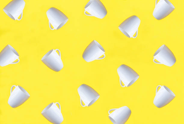 White coffee cups on the yellow background. Top view. Pattern. Flat lay.