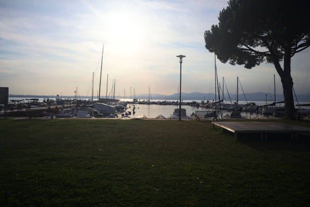 Harbour on a lake with moored boats seen from the lawn in front of it at sunset