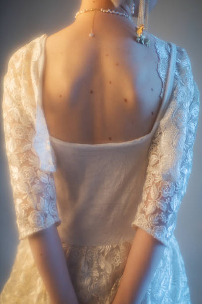 Tall slender African American model with long hair and casual dress poses in studio before a white seamless background.