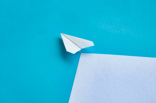 istock Angle view of paper airplane flying on blue background with customizable space for text 2166188980