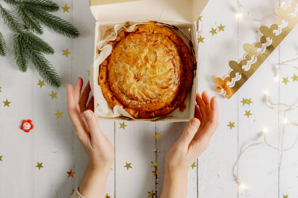istock A woman's hands clasp a box with a royal galette and a crown on the table. 2166194748