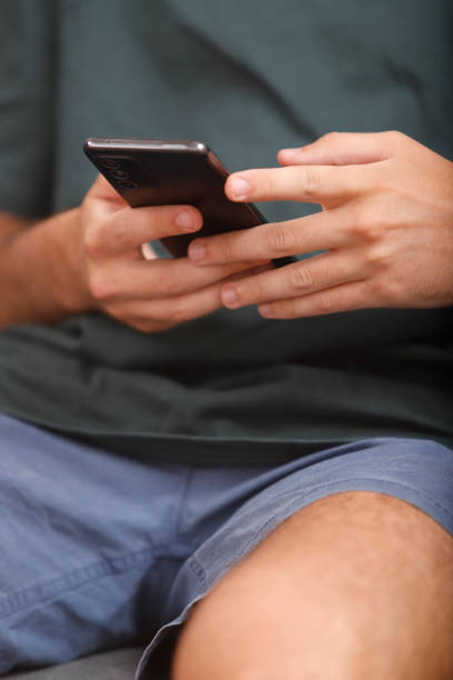 istock man's hands with cell phone 2166198692