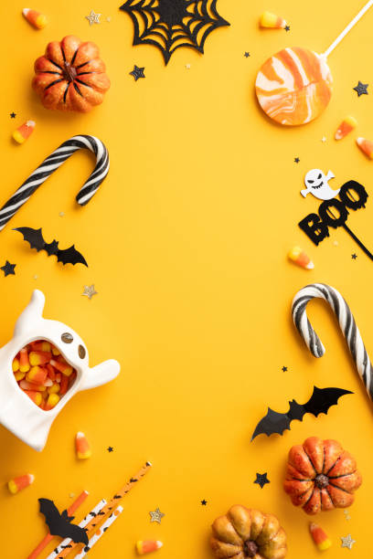 istock Halloween vertical background featuring candy corn, pumpkins, candy canes, and spooky decorations in a vibrant yellow setting 2166202858