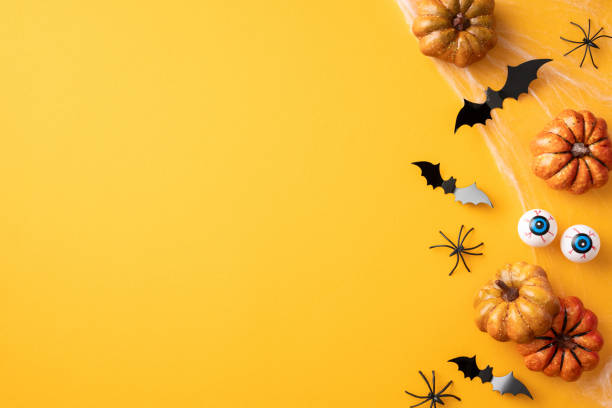 istock Festive Halloween background featuring pumpkins, bats, spiders, and eyeballs arranged on a vibrant yellow surface 2166202867