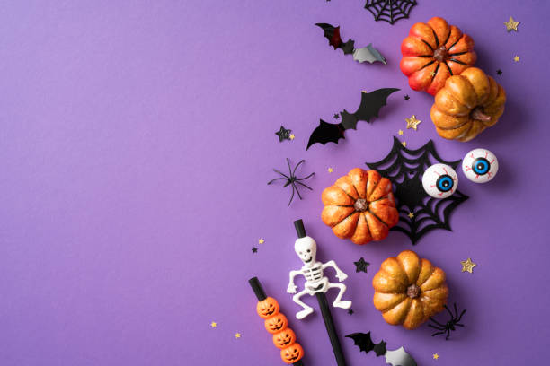 istock Halloween background concept featuring pumpkins, bat decorations, spiders, skeletons, and other spooky elements on a purple surface 2166202868
