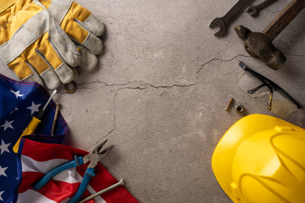 istock Labor Day celebration concept with various construction tools, gloves, American flag, and yellow hardhat on concrete background 2166202873