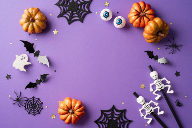 istock Halloween themed background featuring pumpkins, bats, ghosts, skeletons, cobwebs, and eyeballs on a purple surface 2166202884
