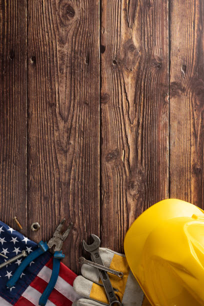 istock Labor Day vertical background with American flag, safety helmet, and work tools on a wooden surface 2166202901