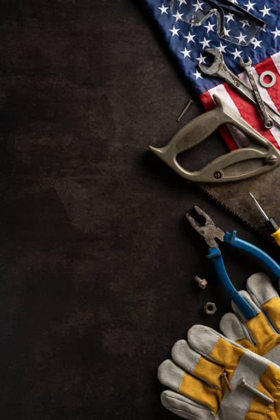 istock Top vertical view of various hand tools and the USA flag on a dark background, symbolizing Labor Day and hardworking spirit 2166202906