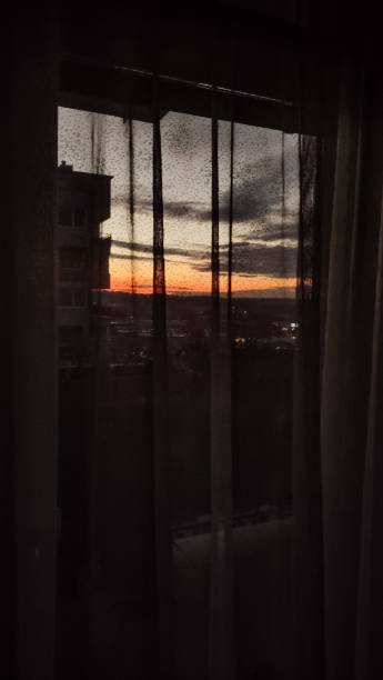 istock A stunning sunset casts vibrant colors beyond sheer curtains. Vertical mobile photo. sstkvertical 2166210590