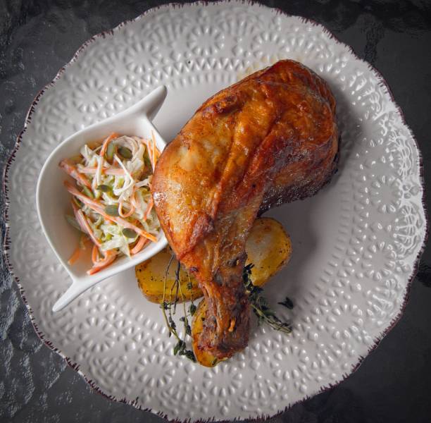 Roasted chicken leg with roasted baby potatoes and coleslaw salad.