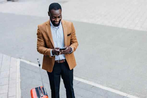 istock Man with a red suitcase using phone in urban setting. 2166213019