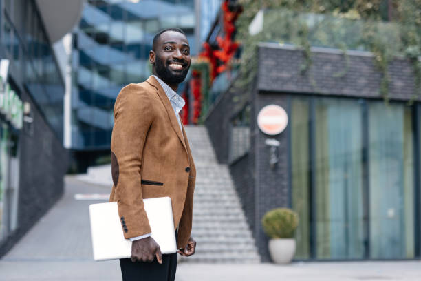 istock Smiling businessman with laptop outside modern building. 2166213035