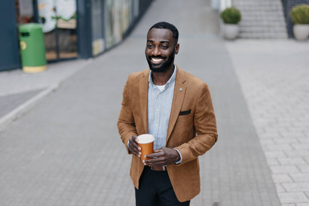 istock Man with coffee cup walking on urban sidewalk smiling 2166213669