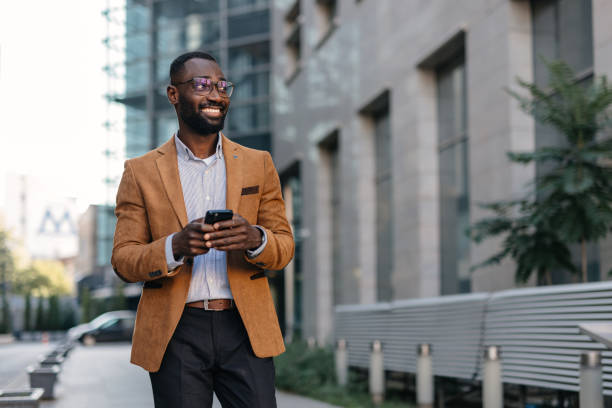 istock Man in brown blazer using smartphone on city street 2166213782