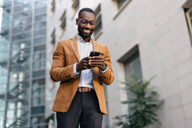 istock Man in brown jacket smiles while using his phone. 2166213805