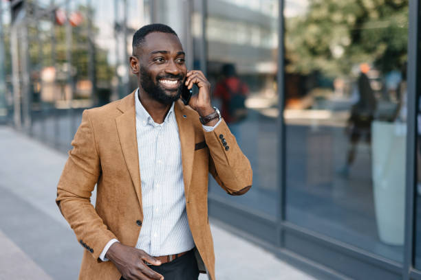 istock Man in brown jacket walks, talks on phone, smiles. 2166213862