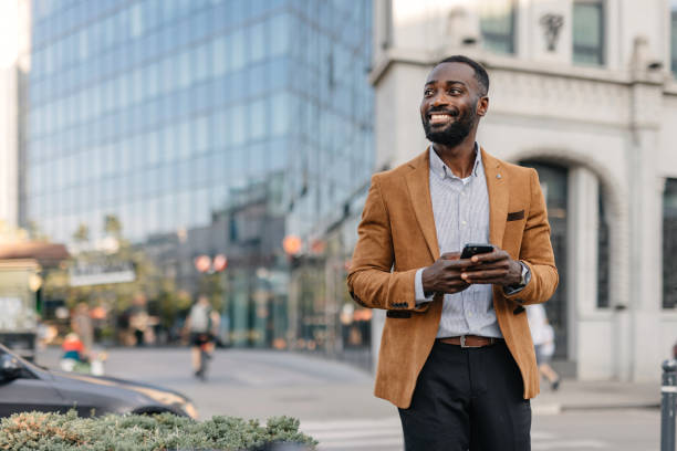 istock Man in brown jacket smiles while using his phone. 2166213899