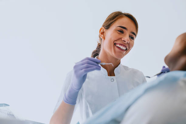 istock Female Dentist Smiling While Treating a Patient in Clinic 2166226976
