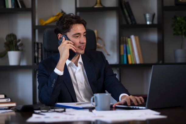istock Young businessman talking on phone while working on laptop in office 2166229290