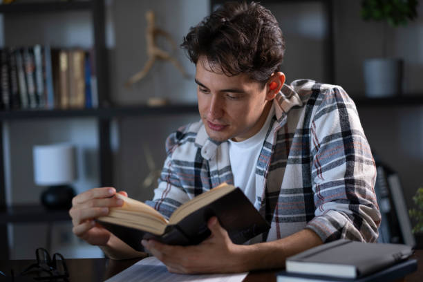 istock Young man reading book at his desk 2166229378