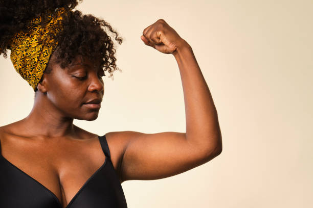 istock Confident black woman wearing headscarf is flexing biceps on white background 2166230642