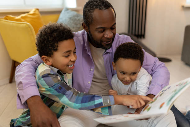 istock Dad and sons reading a book together and looking interested 2166232822