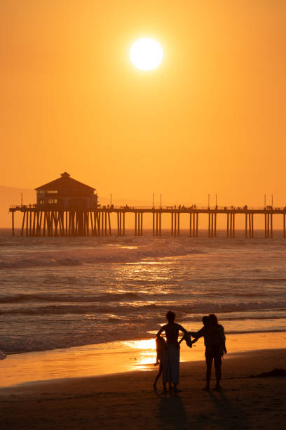 A small group of people in front of the Huntington Beach pier at Golden Hour. The photo was taken in August 2024.