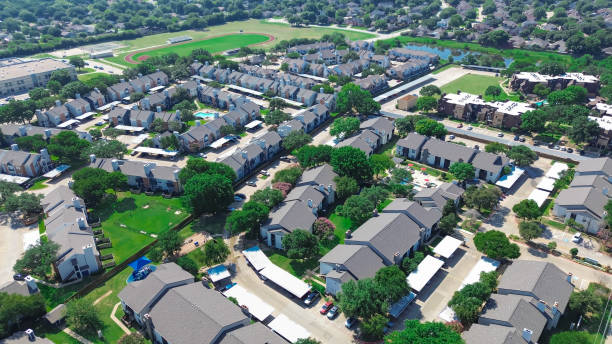 istock Large apartment complex in school district with track and field, multistory townhomes with covered parking garage, swimming pool, dog park and pond, residential neighborhood nearby, aerial view 2166236275