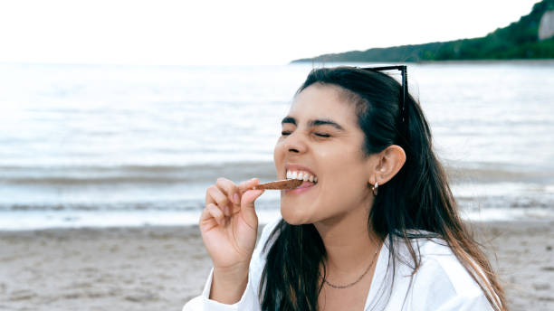 istock A woman is eating a snack on a beach 2166239287