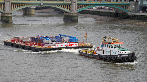 London, United Kingdom - April 09, 2010: Tugboat Pulling Construction Platform Near Blackfriars Bridge at Thames River Spring Day.
